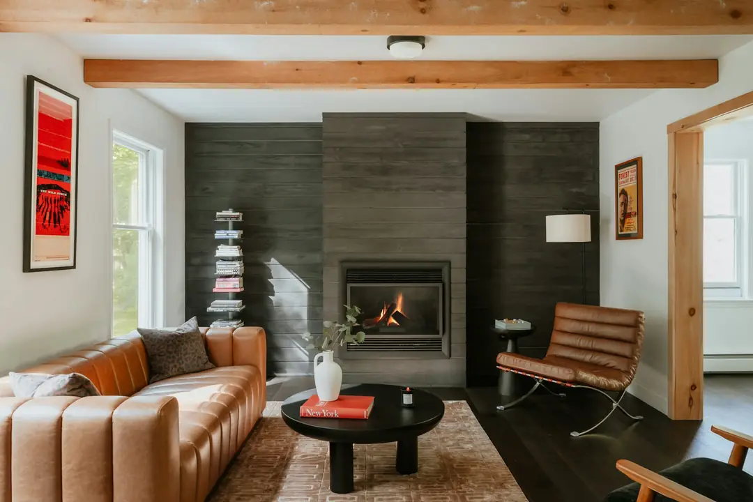 Salon contemporain avec un foyer à bois allumé derrière sa vitre